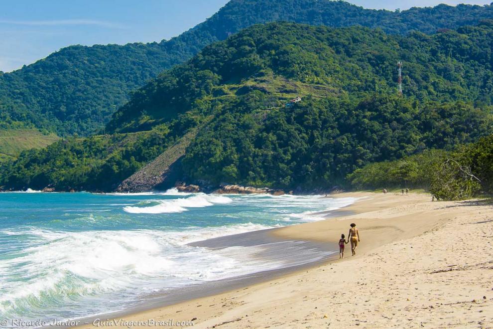 Imagem de mãe e filha andando na beira da Praia do Puruba.